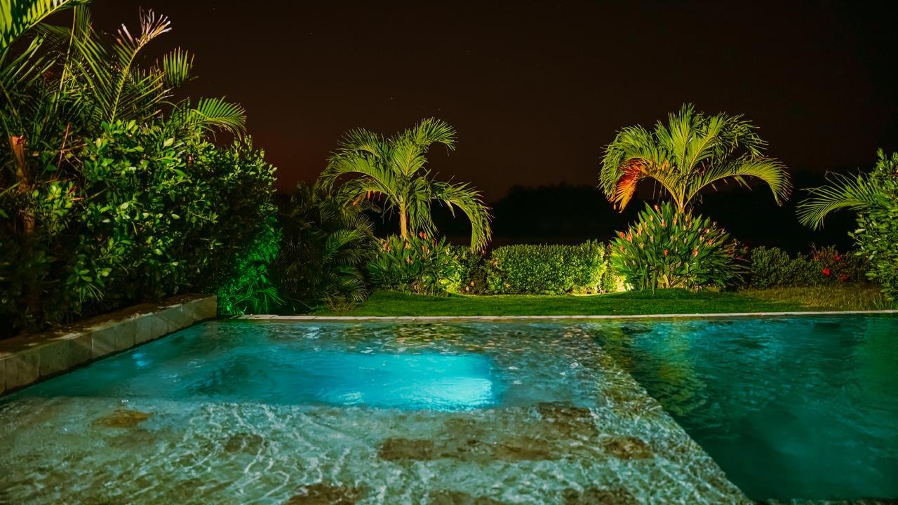 Piscina iluminada y jardín de noche